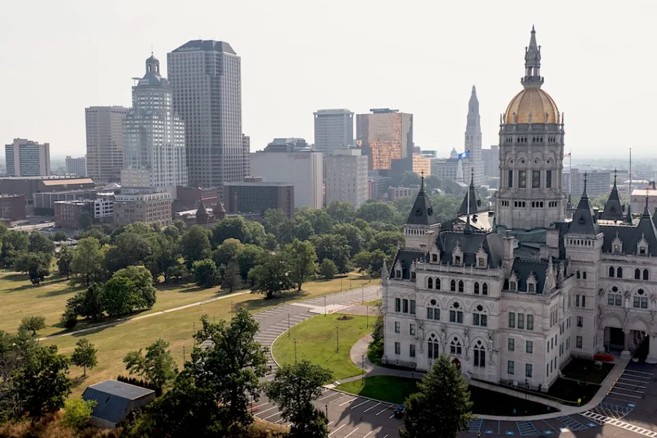 Connecticut state capitol with gold dome and modern office buildings in background in Hartford, CT.
